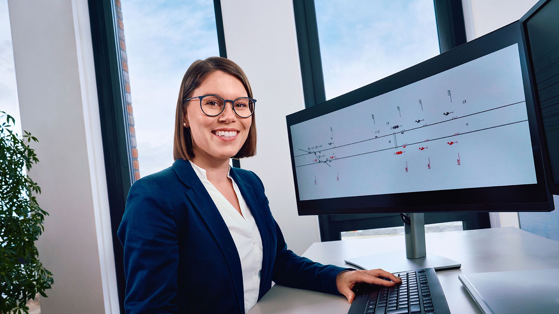 Eine Elektroingenieurin sitzt am Schreibtisch und arbeitet am PC
