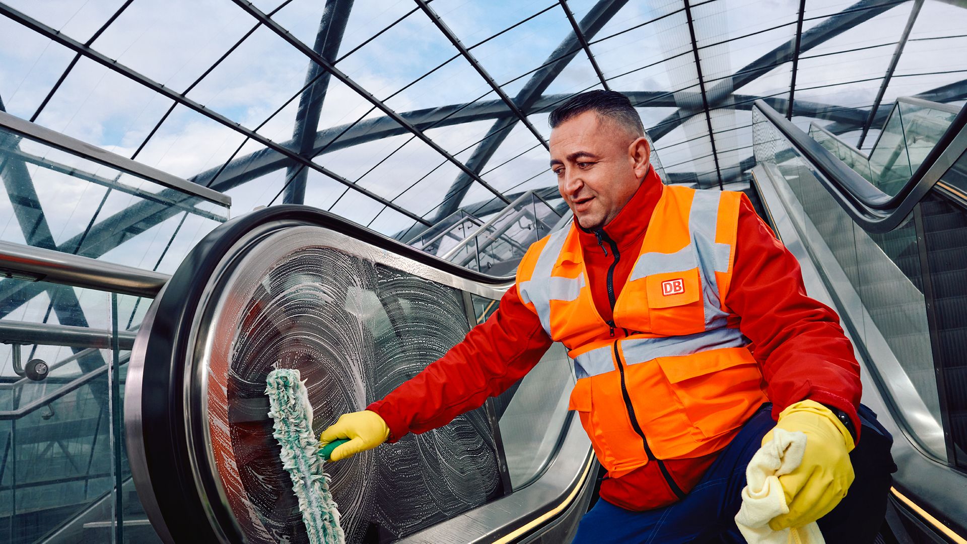 Ein Gebäudereiniger in Arbeitskleidung reinigt eine Rolltreppe