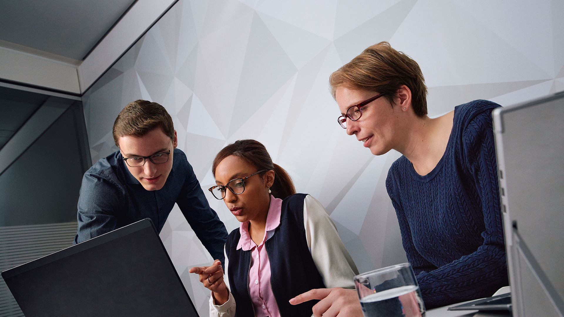 Ein Team von IT-Mitarbeitern sitzt vor einem Bildschirm und diskutiert